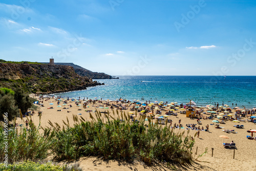 Sunbathers on Golden Bay Beach Malta. Ghajn Tuffieha Tower a Lascaris Tower built in the 17th century can be seen in the background. photo