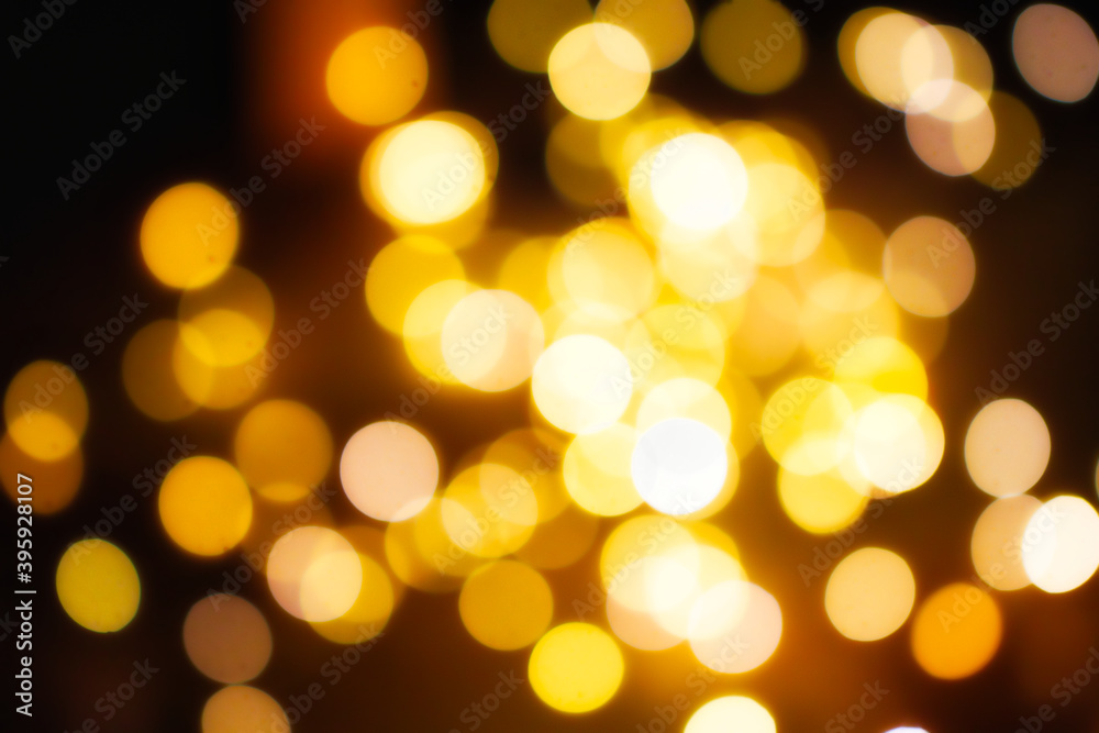 Spirituelle Weihnachtiiche beleuctung in Form eines gelben Bokehs auf einem schwarzen Hintergrund.