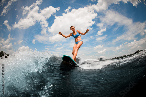 pretty wet woman in blue swimsuit having fun on the board on the river