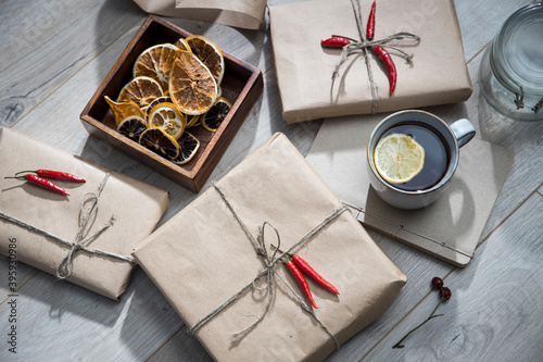 Dry orange circles in a wooden box made of mango wood, wrapped in craft paper and tied with twine, gifts, a mug with tea with lemon. Preparing for Christmas.