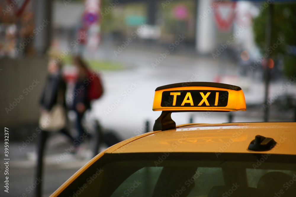 Taxi sign on yellow cab on rainy day