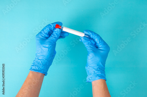 hand in blue gloves holding a test tube
