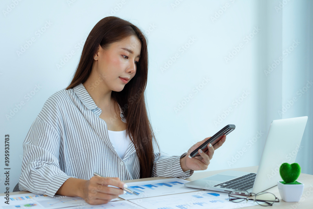 An Asian female finance worker pointing to a graph document showing company profits. To collect information presented to her supervisor, performance audit ideas and financial business. An Asian female finance worker pointing to a graph document showing company profits. To collect information presented to her supervisor, performance audit ideas and financial business.