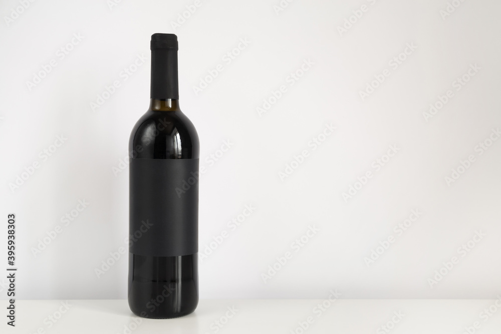 Black bottle of red wine on a white background with copy space. Wine mockup on the table Black bottle of red wine on a white background with copy space. Wine mockup on the table
