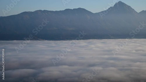 Time lapse elevated view of inversion clouds moving in Alpine valley. Alps mountains in the distance. Static shot, wide angle photo