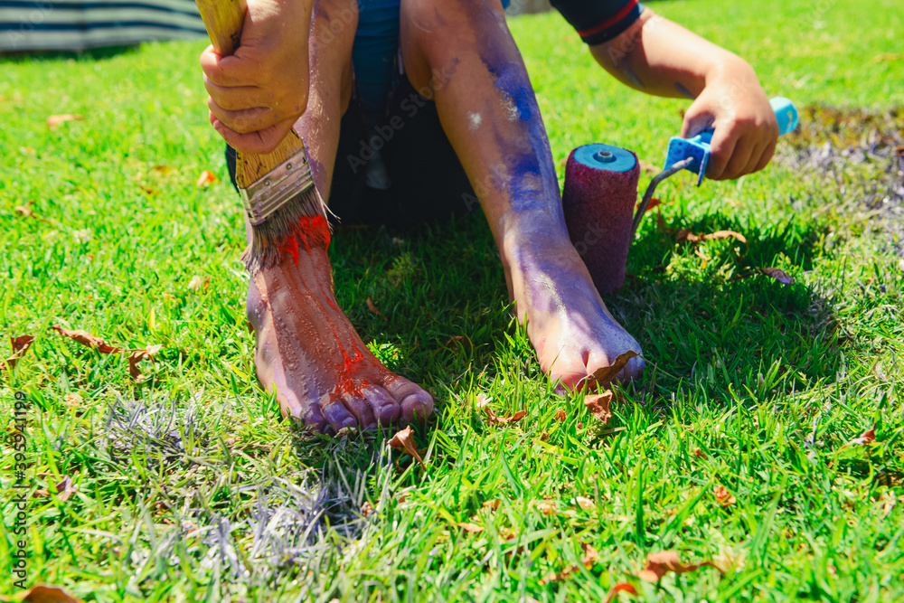 Child in the garden painting himself pink with a paintbrush and a paint roller Child in the garden painting himself pink with a paintbrush and a paint roller