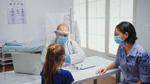 Doctor with protective gloves showing skeleton on tablet to girl. Physician specialist in medicine providing health care services consultation treatment examination in hospital cabinet during covid-19