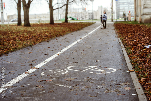 A bike path in city public park on autumn day. A boy standing in the distance