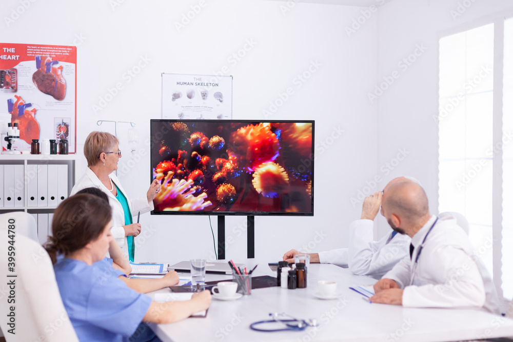 Obraz premium Medical specialist talking about vaccine for coronavirus pandemic during medical meeting with staff. Doctor discussing with colleagues about global pandemic because of dangerous virus, symptoms.