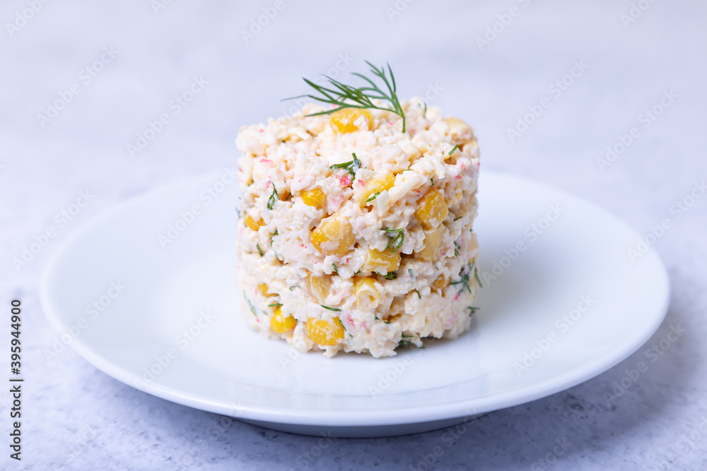 Crab salad with corn and eggs on a white plate. Traditional Russian salad. Close-up. Crab salad with corn and eggs on a white plate. Traditional Russian salad. Close-up.