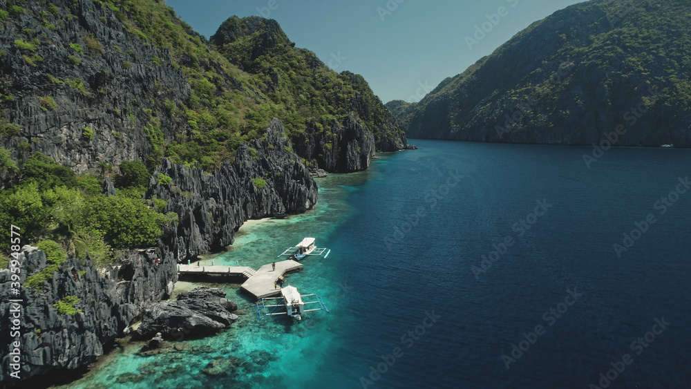 Beautiful exotic nature landscape at mountain island of Palawan, Philippines, Asia. Closeup aerial view of boats at ocean cliff coast with green tropical forest. Cinematic drone soft light shot