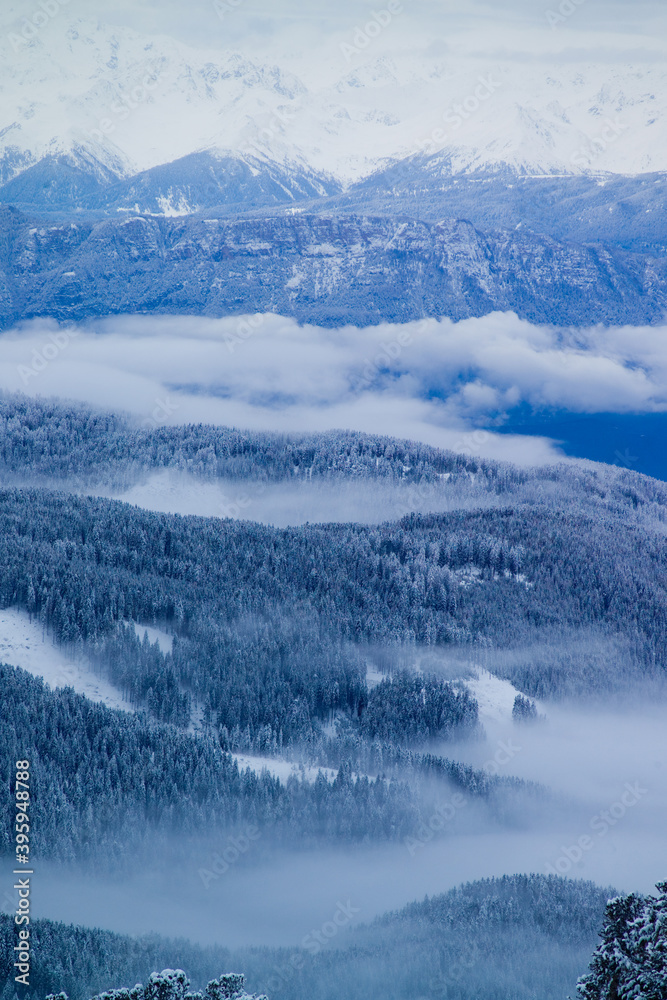 Viste da alta quota della Val di fiemme, con montagne e nuvole basse.