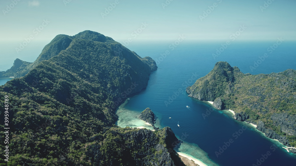 Mountainous greenery islets at sea bay coast aerial view. Amazing seascape of green tropical forest at hilly islands of El Nido, Philippines. Nature scenery of blue ocean water at summer sunny day