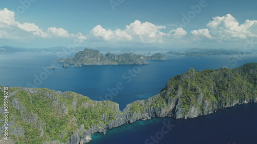 Mountainous tropical islands at ocean bay aerial rise up view. Mountain ranges at tropic isle of El Nido, Philippines. Nobody nature seascape with serene blue water. Cinematic soft light drone shot