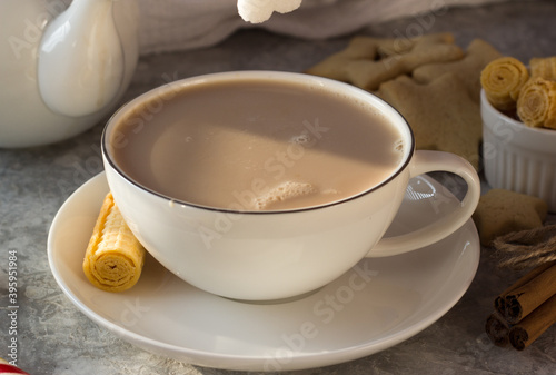 A woman's hand puts a lump of sugar in a white mug of tea