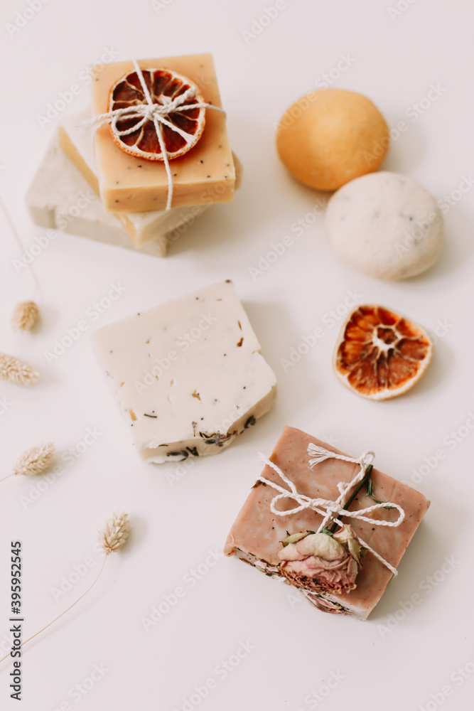 natural homemade soap bars with orange slices and flowers on white background. Spa concept, body care products. top view. 