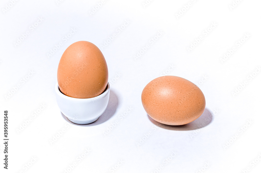 Two farm spotted brown orange chicken eggs in an egg stand and lie on white background. Two farm spotted brown orange chicken eggs in an egg stand and lie on white background.