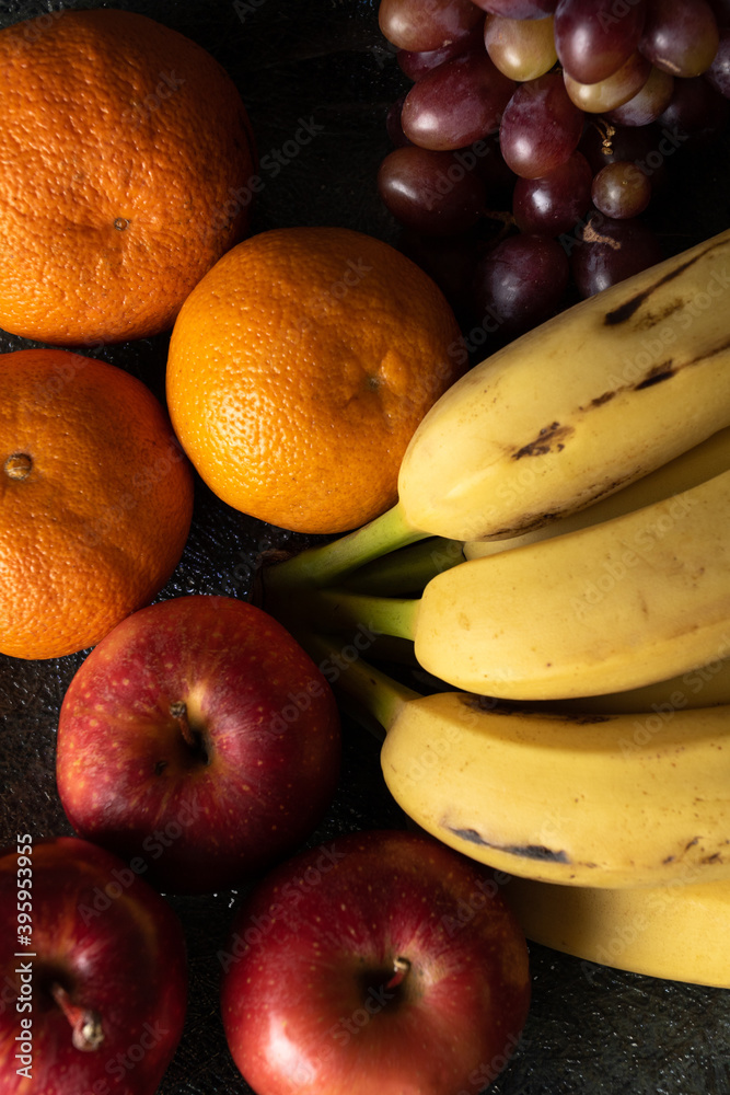 grapes tangerine bananas and apples on a dark pot grapes tangerine bananas and apples on a dark pot