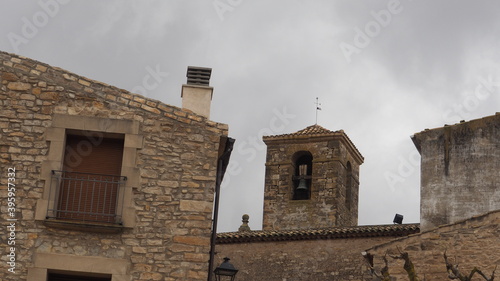 campanario de la iglesia de piles, de torre cuadrada de piedra y techumbre de teja roja, con una campana de broce, tarragona, españa, europa