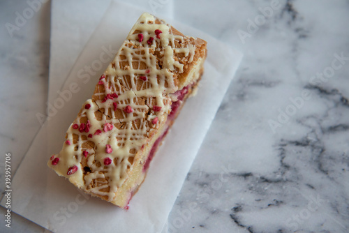 Raspberry and white chocolate cake slice on a white marble background 