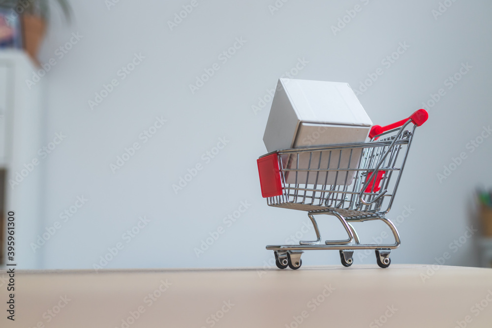 Concept of online shopping: Little shopping cart on white box Concept of online shopping: Little shopping cart on white box