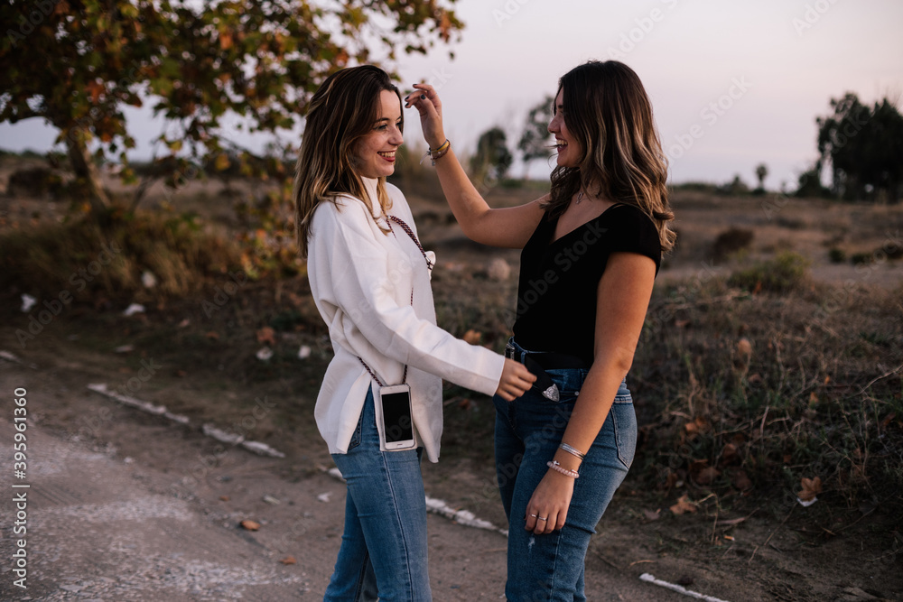 Fototapeta premium Lesbian women couple smiling while showing love. They are dressed casually. One girl touches her hair and the other girl her waist