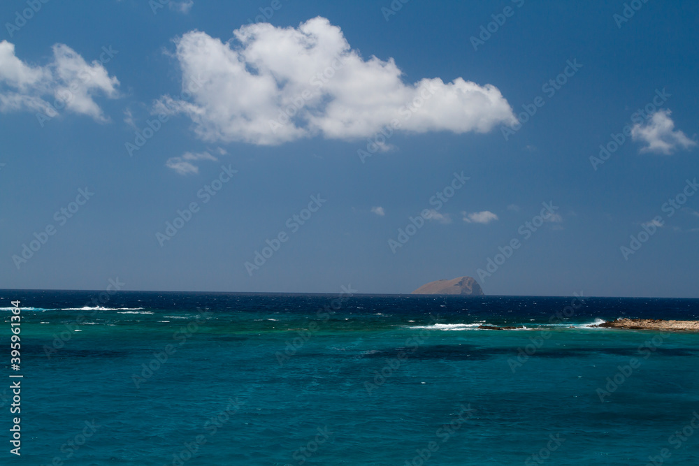 Fototapeta premium blue clear sea and waves on the surface and rocks and mountains during the day is blue sky in the sky clouds in greece