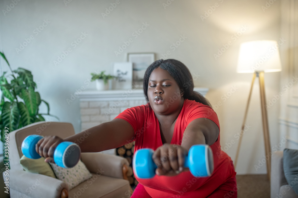 Plus size african american woman doing squats with dumbbells Plus size african american woman doing squats with dumbbells