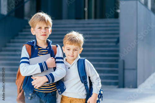 Two blond boys pupils of primary school. Three children near building outdoors. Beginning of lessons. First day of fall. © Iryna