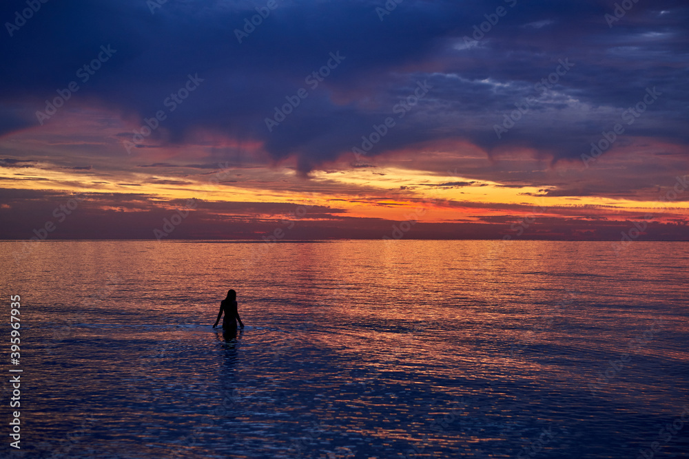 Silhouette of a woman in the water at sea dawn.