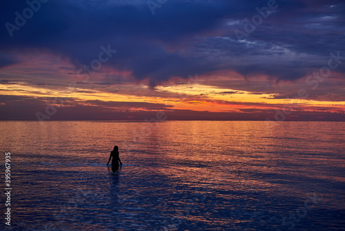 Silhouette of a woman in the water at sea dawn.