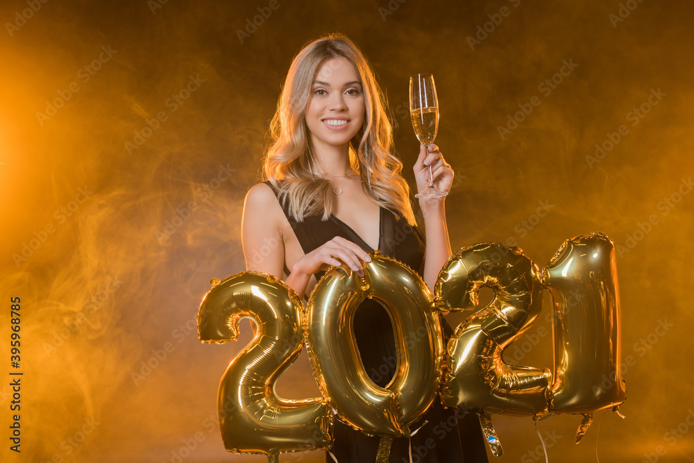  blonde woman holding balloons with 2021 numbers on black with smoke