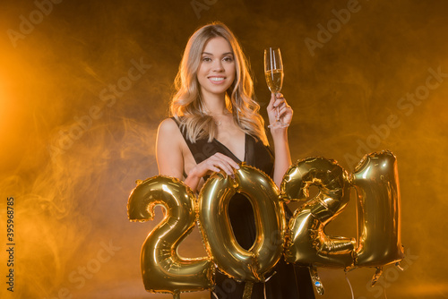  blonde woman holding balloons with 2021 numbers on black with smoke