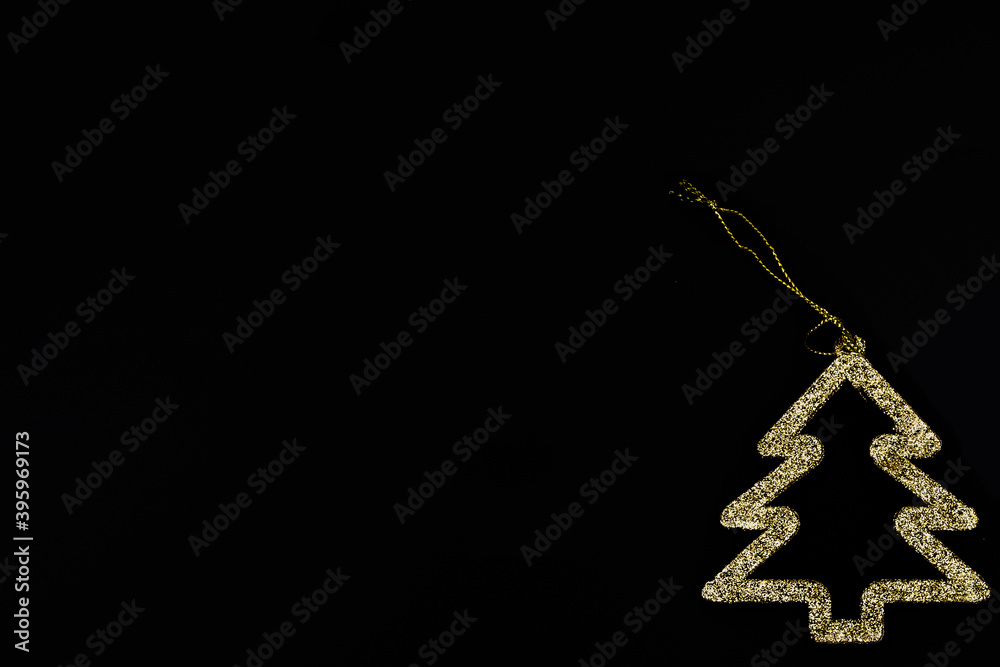 Fototapeta premium Minimalistic golden Christmas tree on a black background. New year simple composition. Merry Christmas and happy New Year greeting card.