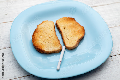 The harm of smoking to the lungs concept. Toasted white bread and a cigarette on a plate.