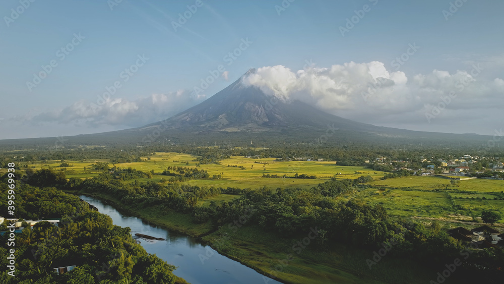 Hillside river at erupt volcano with green grass shore at Philippines countryside aerial. Fields, valley, meadows of nobody nature landscape. Cinematic scenic of Mayon mount erupt at mist haze