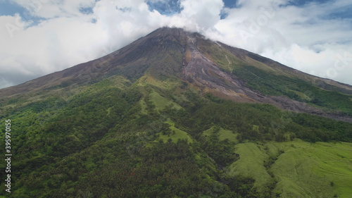 Closeup volcano top erupt clouds of haze aerial. Green grass mountain with hiking path. Philippines landmark of Mayon Mount, Legazpi countryside. Nobody nature landscape at fog. Cinematic drone shot