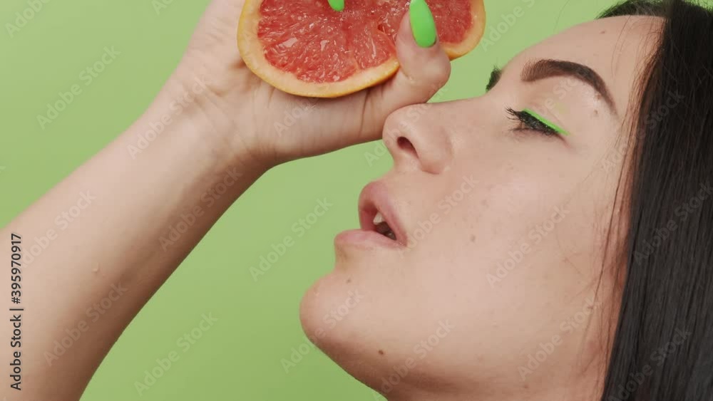 girl with a drop of grapefruit s juice in her fingers with bright manicure