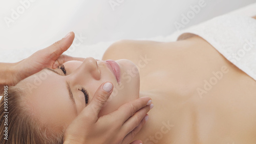Young  beautiful and healthy woman in massaging salon. Traditional face massage therapy and skin care.