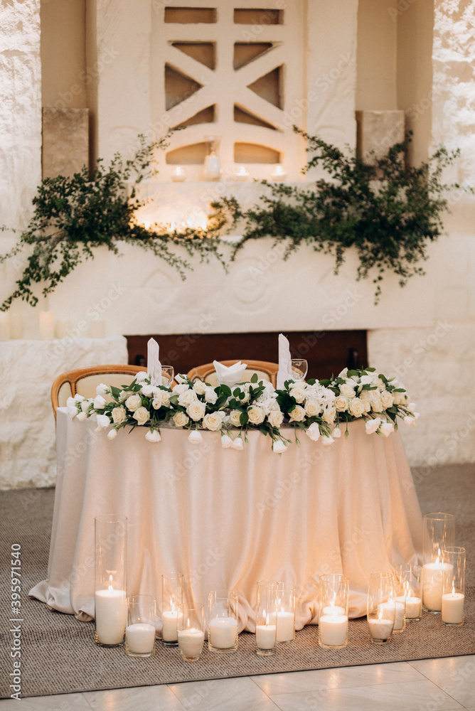 the presidium of the newlyweds in the banquet hall of the restaurant is decorated with candles and green plants the presidium of the newlyweds in the banquet hall of the restaurant is decorated with candles and green plants