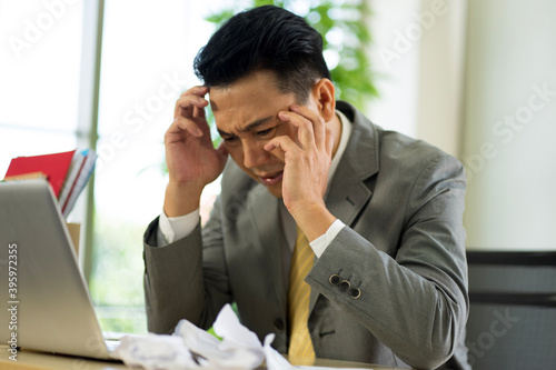 depressed worry Asian businessman wearing formal suit in the office feeling stressful from financial problem caused by virus pandemic. 