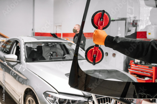 Automobile technician worker replacing windscreen or windshield of a car in auto service station garage. High quality photo photo