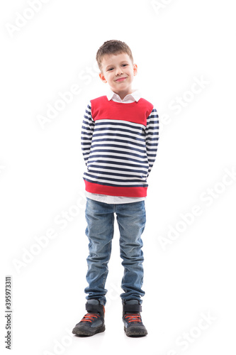 Фотография Cute stylish charming cool little boy in sweater posing with hands behind back