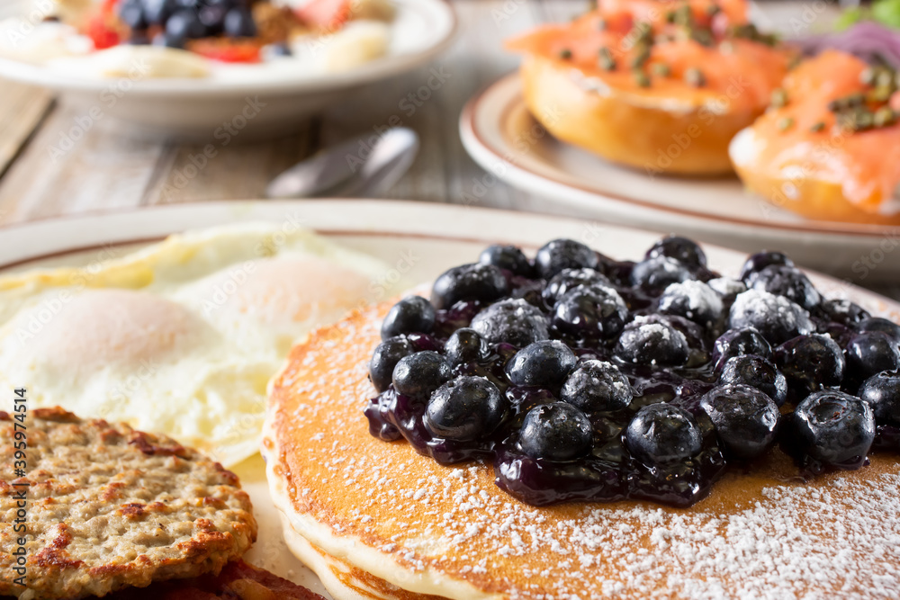 A closeup view of a pancake breakfast plate featured with several other breakfast and brunch plate on a table. A closeup view of a pancake breakfast plate featured with several other breakfast and brunch plate on a table.