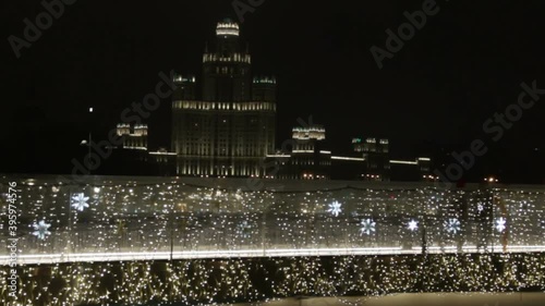 luminous bright snowflakes yellow coloured light bulbs of garland. Christmas street decorations, new year preparation in city. People walk on decorated bridge in the evening