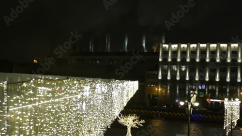 luminous bright snowflakes yellow coloured light bulbs of garland. Christmas street decorations, new year preparation in city. Old factory building with pipes