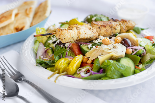 A view of a grilled chicken greek salad, in a restaurant or kitchen setting.