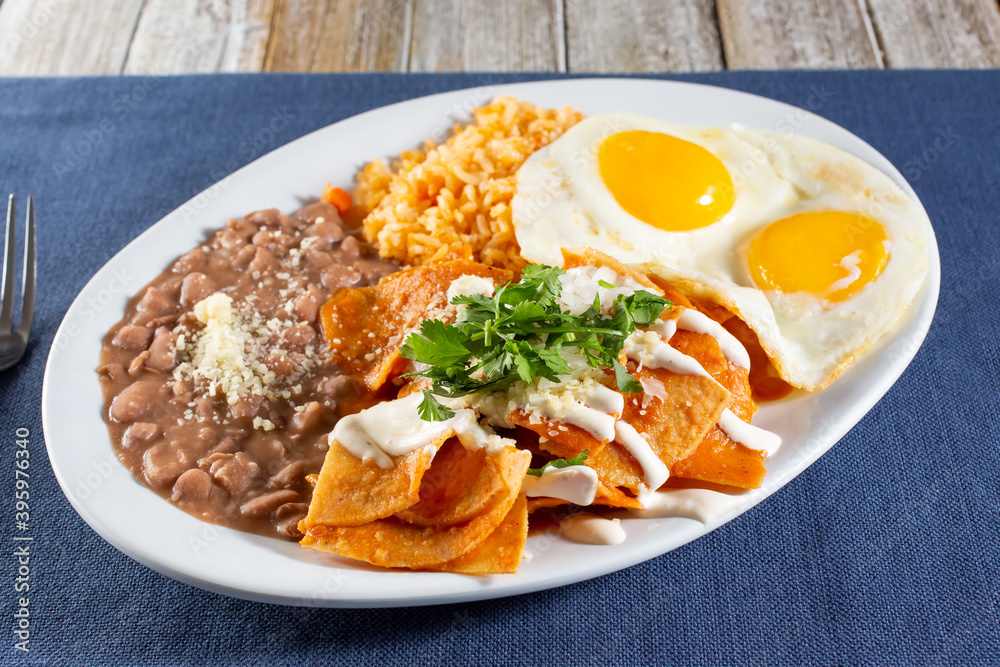 A view of a plate of chilaquiles and huevos, with rice and beans. A view of a plate of chilaquiles and huevos, with rice and beans.