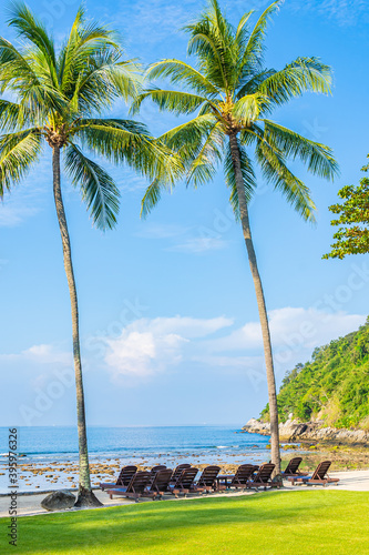 Beautiful tropical coconut palm tree with chair around beach sea ocean with white cloud on blue sky