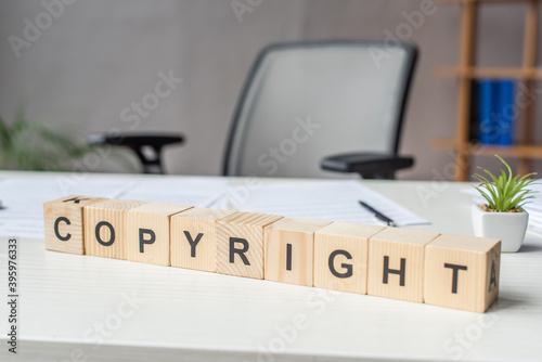 Close up of wooden cubes with copyright lettering with blurred workplace 